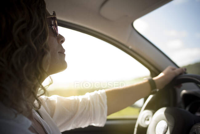 Close up de mulher bonita com óculos de sol dirigindo um carro. — Fotografia de Stock