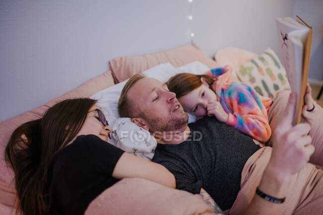 Горизонтальный макро отца чтение детям в постели — стоковое фото