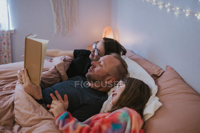 Retrato de padre leyendo a hijas - foto de stock