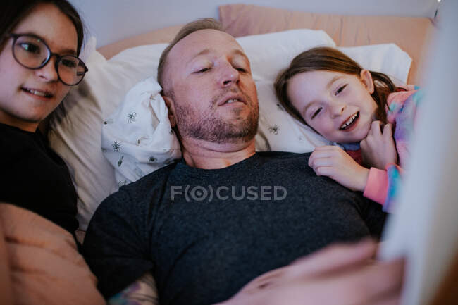 Primer plano de papá leyendo a chicas felices - foto de stock