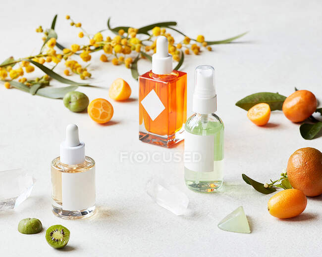 Botellas e ingredientes cosméticos orgánicos naturales sobre fondo blanco - foto de stock