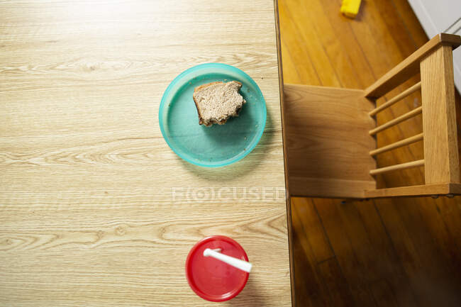 Sandwich de mantequilla de maní en colorido plato infantil con silla vacía - foto de stock