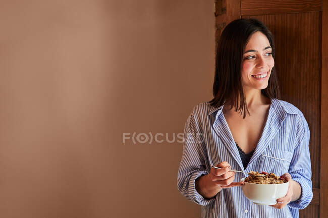 Jeune femme prenant le petit déjeuner à côté d'une fenêtre à la maison. Espace de copie — Photo de stock