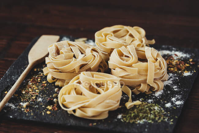 Preparazione ingredienti per spaghetti su un piatto nero e tavolo di legno — Foto stock