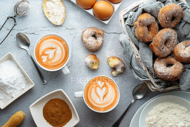 Café com arte latte e pequenos donuts com açúcar e canela e ingredientes. Sobremesa de donuts — Fotografia de Stock