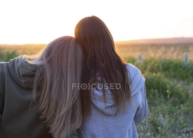 Две девушки спина к спине наблюдают за закатом — стоковое фото