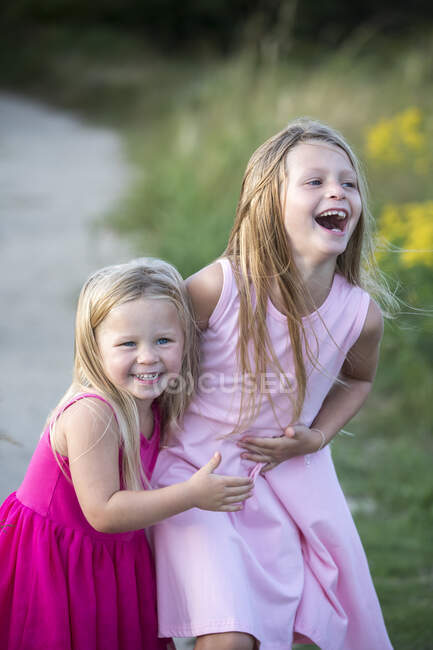 Jovens Irmãs rindo em vestidos de verão rosa — Fotografia de Stock