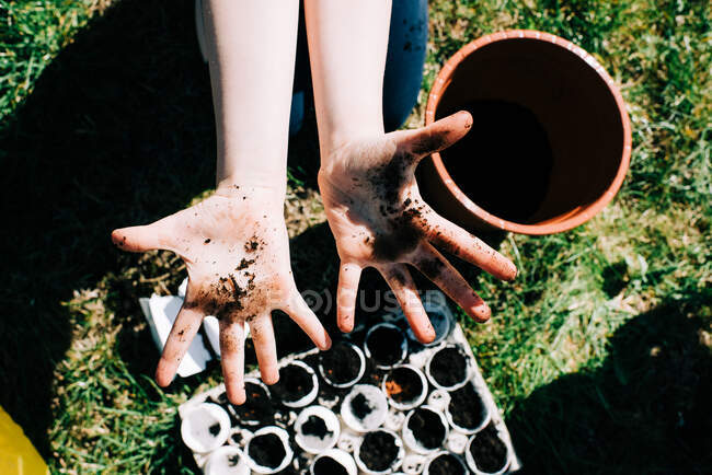 Childs dirty hands from planting seeds in egg shells outside — Stock Photo