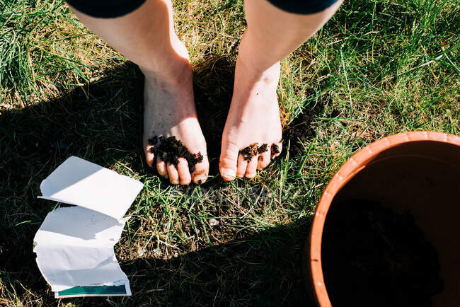 Mädchen Füße bedeckt mit Erde und Samen von der Pflanzung im Garten — Stockfoto