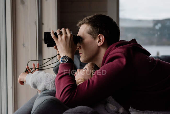 Father and daughter looking through binoculars at the snowy view — Stock Photo