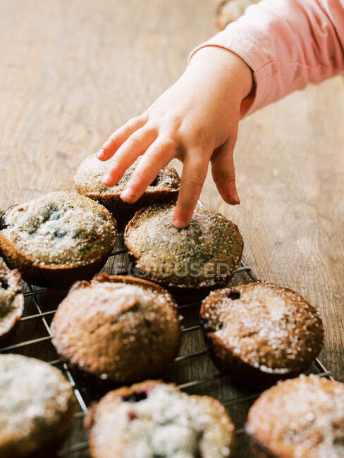 Child hand touching homemade cupcakes — Stock Photo