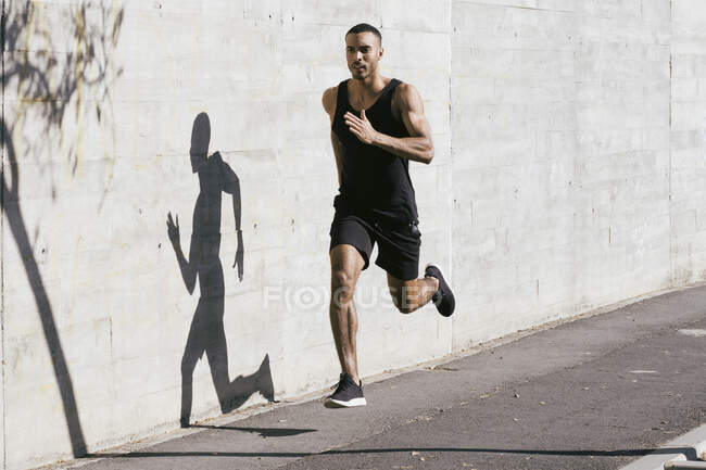 По всей длине афроамериканский спортсмен бежит к бетонной стене — стоковое фото