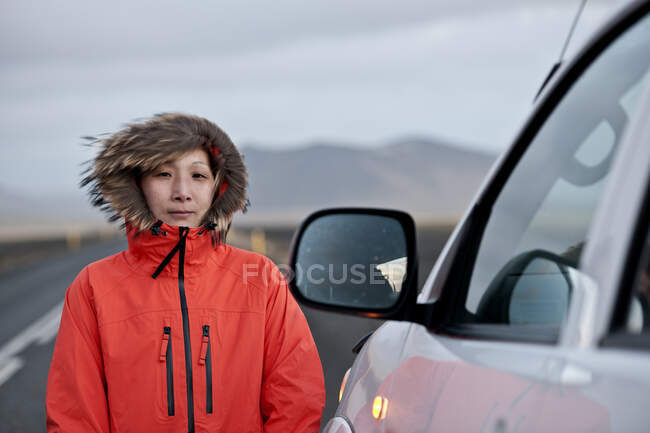 Woman standing next to SUV on empty highway — Stock Photo