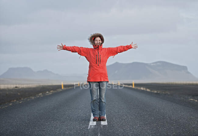 Femme debout au milieu de la route avec les bras tendus — Photo de stock