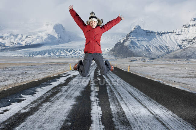 Mulher pulando no meio de uma estrada na Islândia — Fotografia de Stock