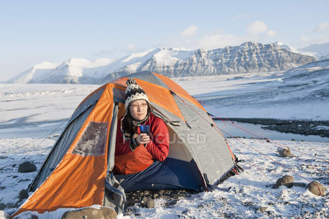 Woman drinking hot beverage at winter camp in Iceland — Stock Photo