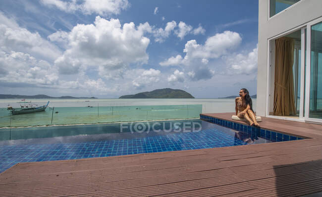 Schöne Frau sitzt am Pool einer Luxusvilla in Phuket — Stockfoto