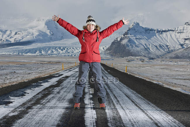 Жінка стоїть посередині шосе з витягнутими руками. — стокове фото