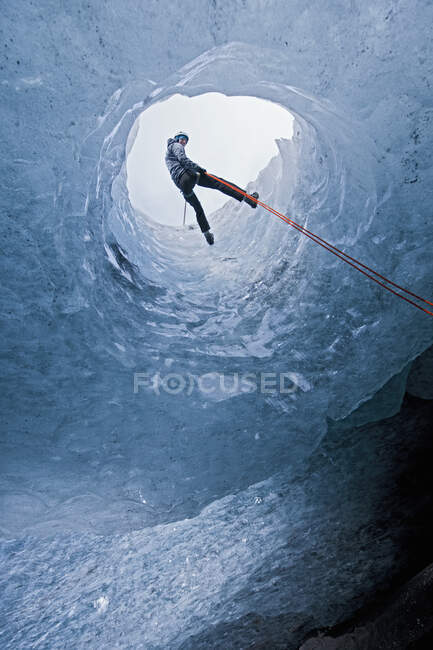 Человек, спускающийся в ледниковую пещеру на леднике Slheimajkull в Исландии — стоковое фото
