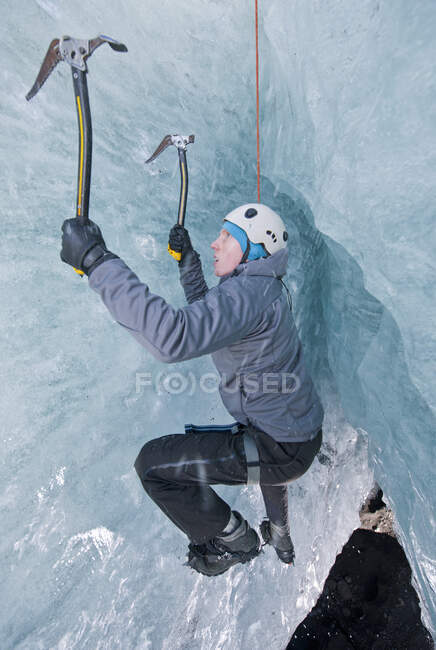 Hombre saliendo de la cueva glaciar / glaciar Slheimajkull en Islandia - foto de stock