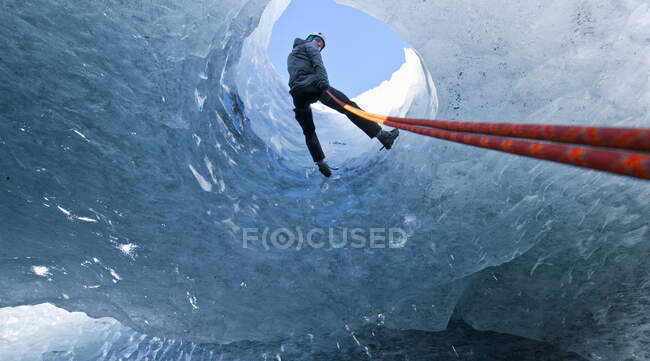 Man rappelling into glacier cave in Iceland — Stock Photo