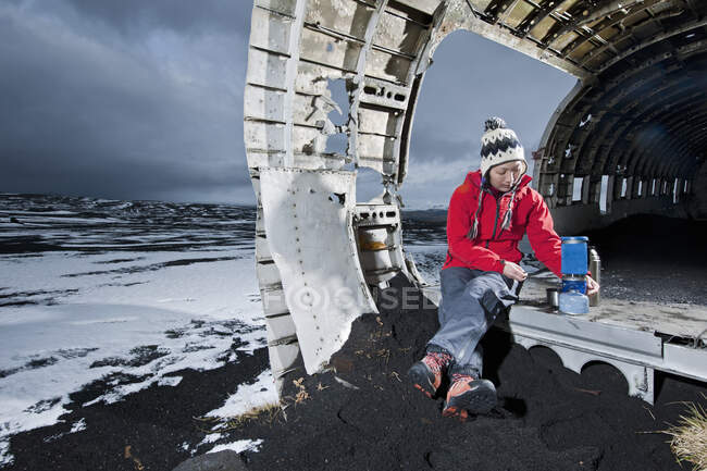 Mulher cozinhar refeição no fogão de campismo no famoso naufrágio avião na Islândia — Fotografia de Stock