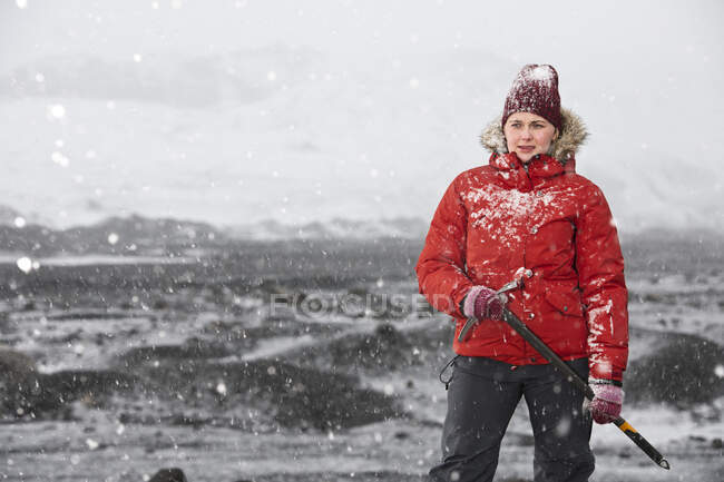 Mulher de pé e segurando machado de gelo perto da geleira na Islândia — Fotografia de Stock