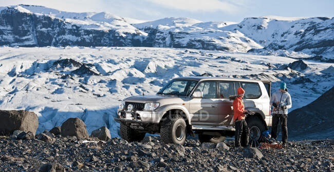 Pareja joven preparándose para caminar desde su SUV en Islandia - foto de stock