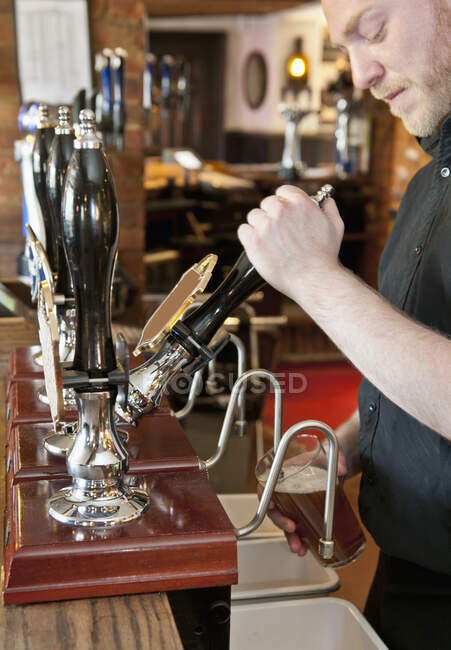 Camarero tirando de la cerveza en el pub británico - foto de stock