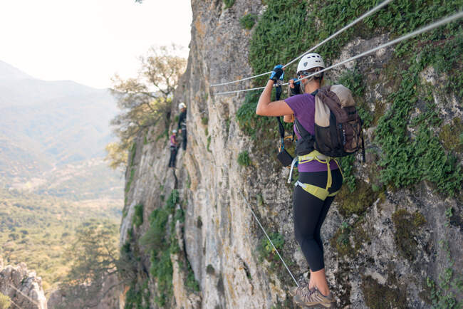 Frau mit Helm, Geschirr und Rucksack. Gehen auf einer tibetischen Brücke. Klettersteige in den Bergen. — Stockfoto