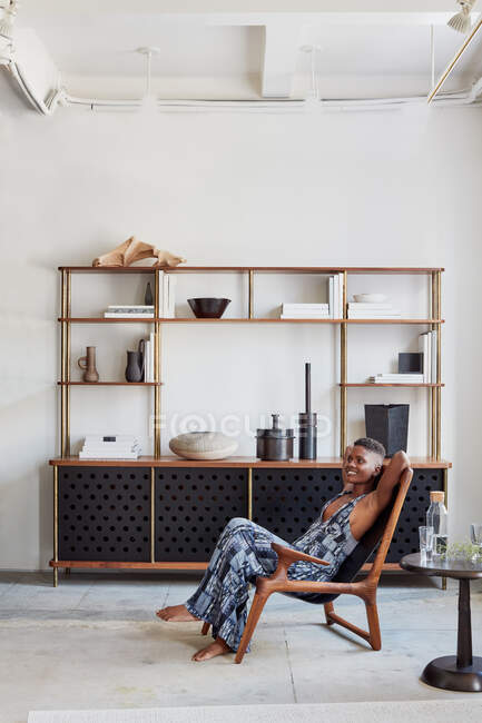 Woman lounging in wood chair with bespoke livingroom console — Stock Photo