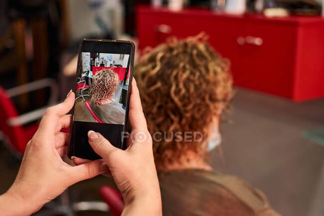 Cabeleireiro tira uma foto de seu trabalho depois de cortar o cabelo de um cliente — Fotografia de Stock