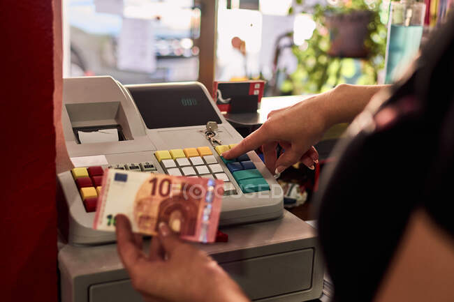 A hairdresser puts her money in her cash register. Small business — Stock Photo