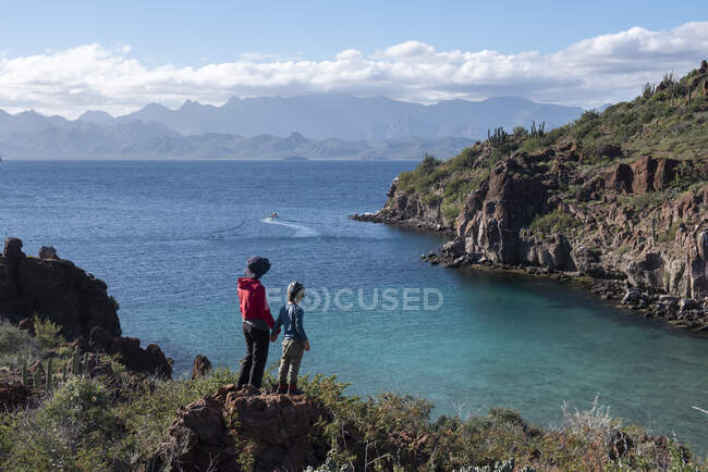 A woman and her son standing on a rock at a beach in Del Carmen Island — Stock Photo