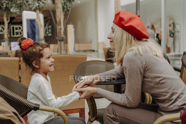 Mom and daughter holding hands in a coffee shop. — Stock Photo