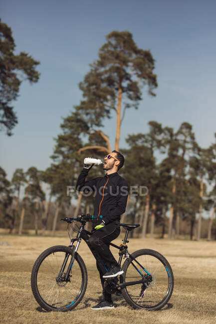 Un motociclista descansando y bebiendo agua - foto de stock