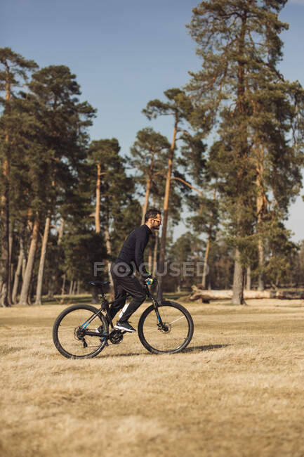 Молодий чоловік їде на велосипеді на трав'яному полі — стокове фото