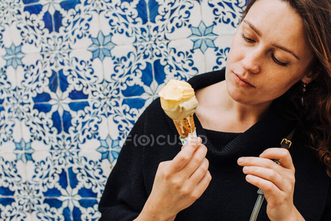 Тысячелетняя женщина с веснушками смотрит на таяние мороженого — стоковое фото