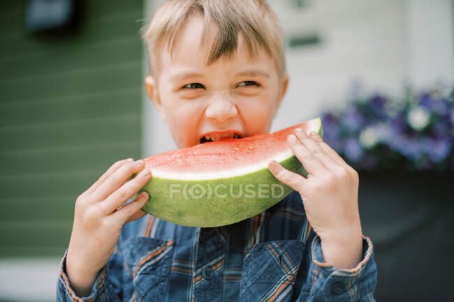 Un niño tomando un gran bocado de su sandía - foto de stock