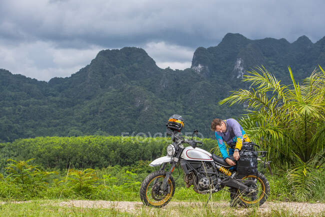 Hombre empacando su motocicleta tipo scrambler en las montañas de Tailandia - foto de stock