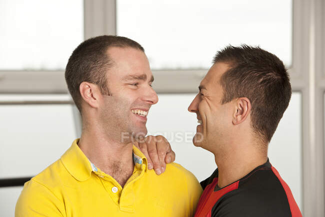 Gay pareja abrazando en gimnasio en el Reino Unido - foto de stock