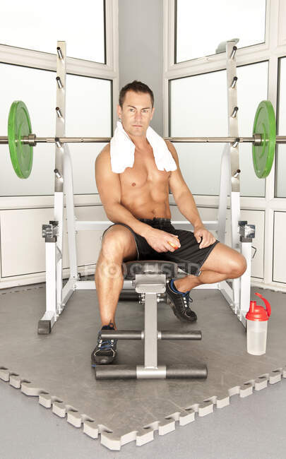 Hombre sentado en el banco en el gimnasio en el Reino Unido - foto de stock