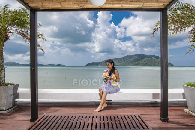 Hermosa mujer disfrutando de jugo de coco en la azotea del complejo de lujo - foto de stock