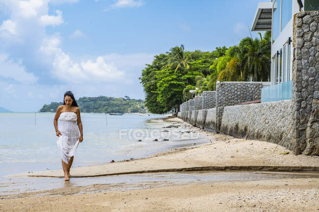 Красуня в білій сукні, що йде по пляжу в Пхукеті. — стокове фото