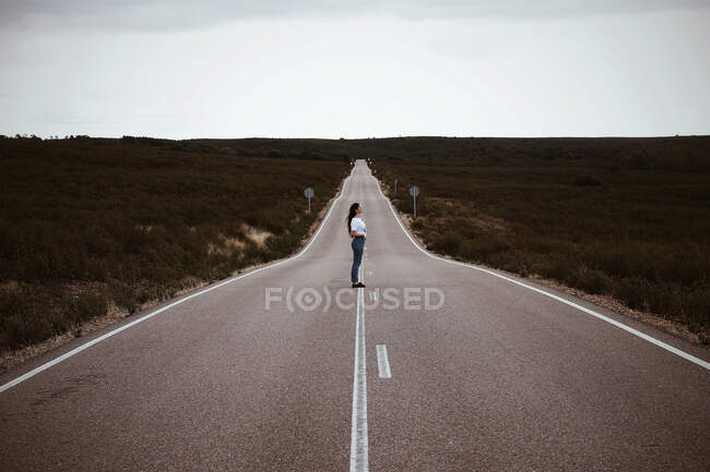 Giovane ragazza spagnola, nel bel mezzo di una strada solitaria, durante l'estate. — Foto stock