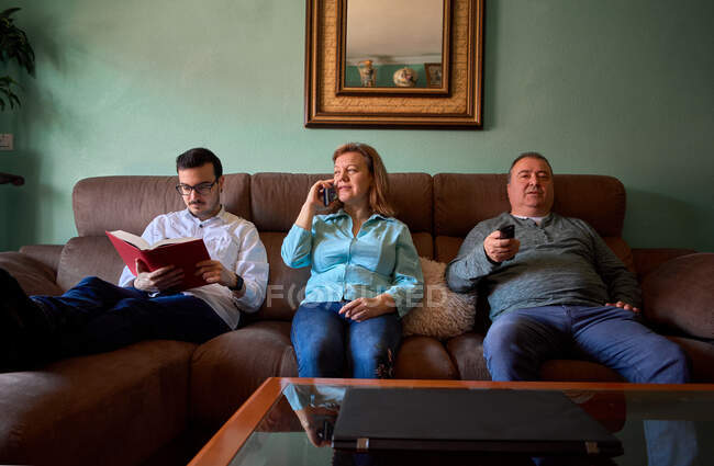 Los miembros de la familia hacen diferentes cosas en su sala de estar - foto de stock