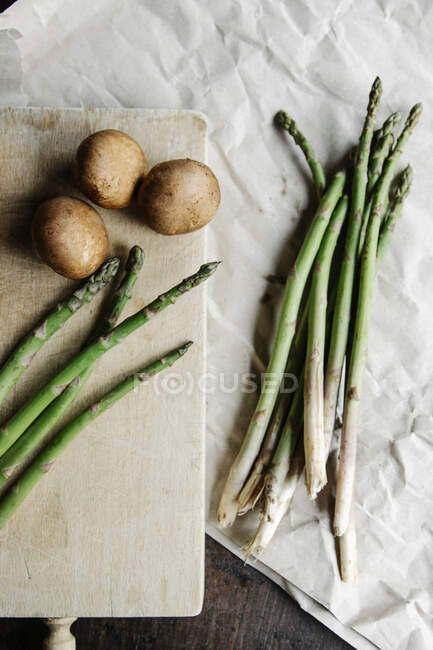 Espárragos verdes frescos y patatas en el fondo - foto de stock