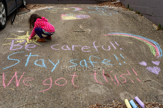 Little girl coloring with chalk social distancing encouragement — Stock Photo