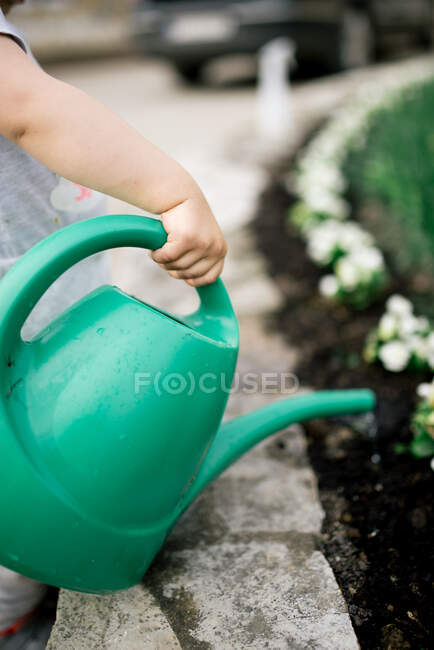 Enfant avec arrosoir dans le jardin en arrière-plan, gros plan — Photo de stock