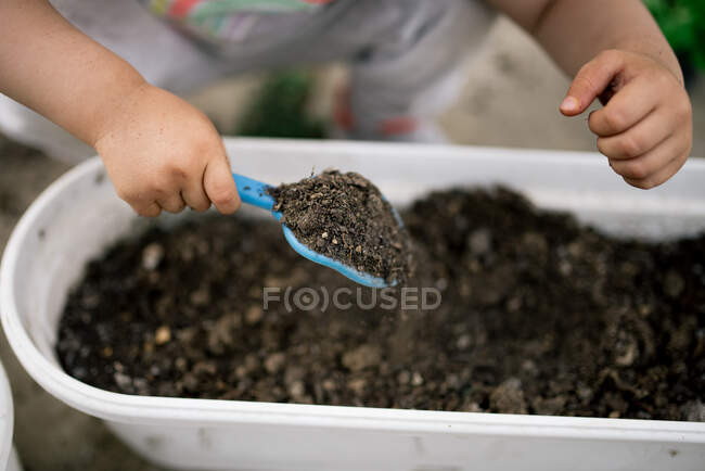 Маленька дівчинка з грунтом в саду на фоні, крупним планом — стокове фото